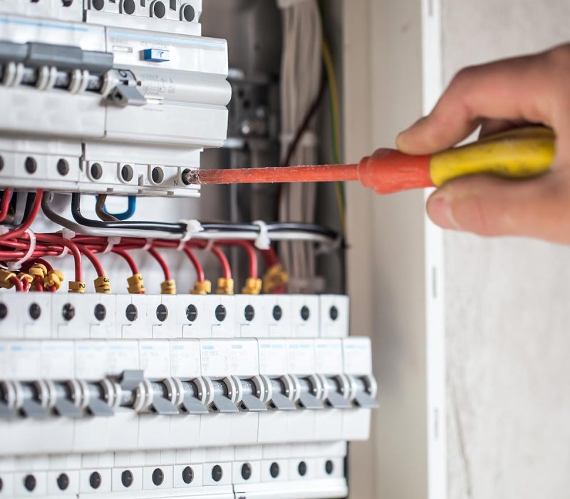 Man, an electrical technician working in a switchboard with fuses. Installation and connection of electrical equipment. Close up.